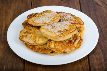 White plate with pancakes on wooden table