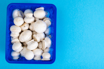 Fresh little white champignons in blue plastic form