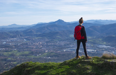 Naklejka na ściany i meble The girl at mountain top. Successful woman backpacker looking at the city.
