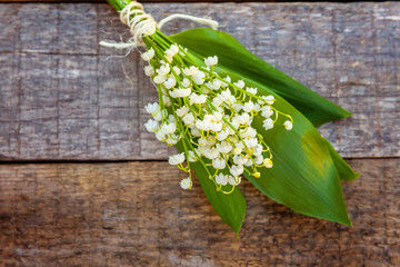 Bouquet of flowers beautiful smell lily of the valley or may-lily on rustic old vintage wooden background, top view flat lay. Garden in spring or summer concept
