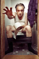 Aging man in a-shirt enjoying his moment on toilet