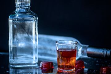 Vodka bottle with glasses and a red ice, vodka and whiskey in glass with ice, alcoholic drink