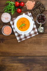 Red lentil soup in plate on wooden background