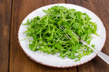 Obraz na płótnie Canvas Vegetarian dish, plate with green arugula on wooden table