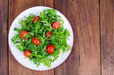 Plate with light dietary salad of arugula and cherry tomatoes