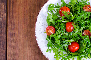 Plate with light dietary salad of arugula and cherry tomatoes