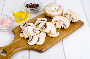 White fresh sliced champignons in pan on kitchen table. The concept of cooking mushroom dishe