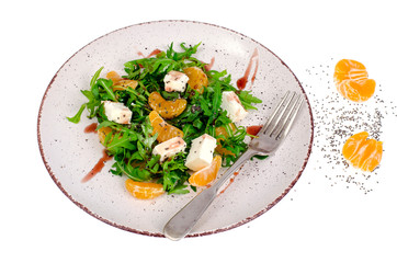 Delicious fruit and vegetables salad. Tangerine, feta cheese, arugula and chia seeds in plate. Healthy food concept