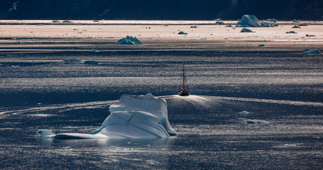 arctic landscape with classic sailing ship and icebergs among east Greenland fjords