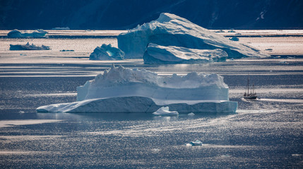 arctic landscape with classic sailing ship and icebergs among east Greenland fjords