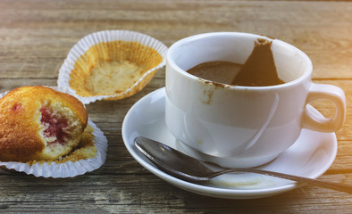 On a wooden table is an empty white Cup of coffee