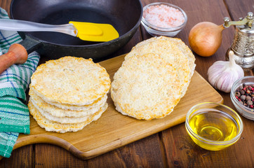 Frozen raw potato pancakes on cutting board for cooking