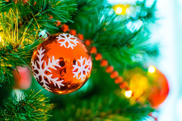 Red Christmas ornament with white snowflake on a green Christmas tree