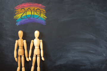 Hugging wooden figures on chalked rainbow background