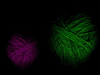 Multi-colored skeins of wool on a black background. Multicolored balls. Colored wool in the balls.