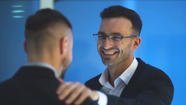 The happy businessmen pat shoulder on the blue background. slow motion