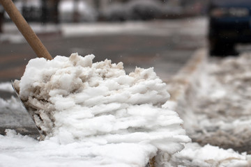 Man with snow shovel cleans sidewalks in winter.