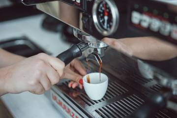 Professional espresso machine pouring fresh coffee into white ceramic cup