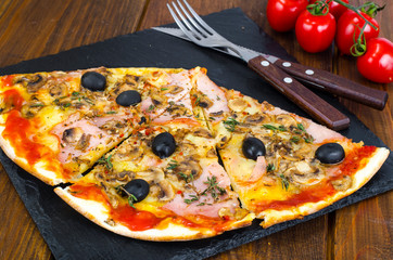 Pizza with Mozzarella cheese, ham, tomato sauce, salami, pepper, spices on wooden table background