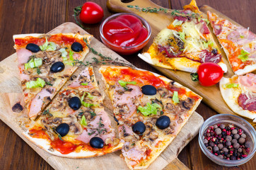Wooden boards with sliced different pizzas