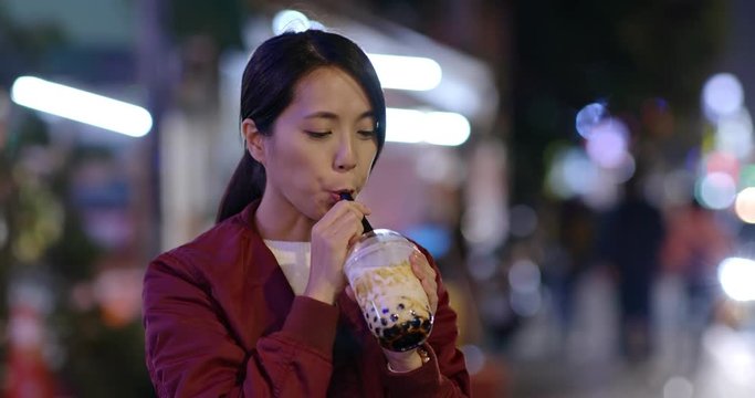 Woman drink of Taiwan iced bubble tea in the night market