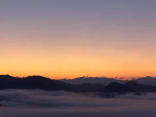 Mountain and foggy at morning time with orange sky, beautiful landscape in the thailand