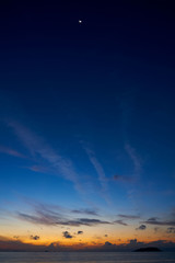 Moon in blue sky before sunrise at Phuket beach