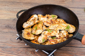 Pan with fried chicken pieces, wooden background