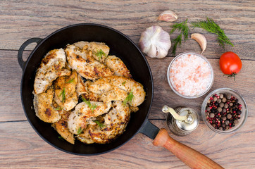 Pan with fried chicken pieces, wooden background