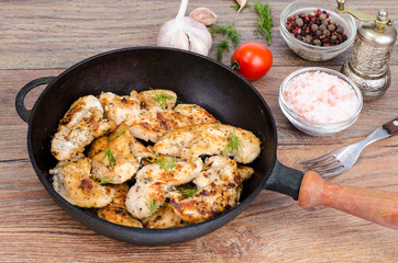 Pan with fried chicken pieces, wooden background