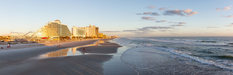 Obraz premium Daytona Beach, Florida, United States - October 31, 2018: Panoramic view of a beautiful sandy beach during a vibrant sunrise.