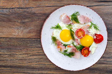 Plate with fried eggs,ham and tomatoes for breakfast