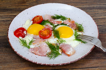 Plate with fried eggs,ham and tomatoes for breakfast