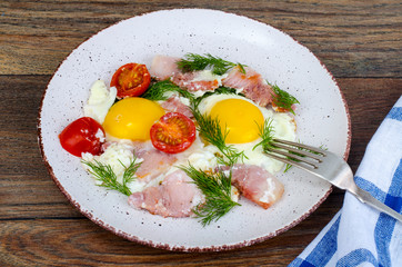 Plate with fried eggs,ham and tomatoes for breakfast