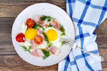 Plate with fried eggs,ham and tomatoes for breakfast
