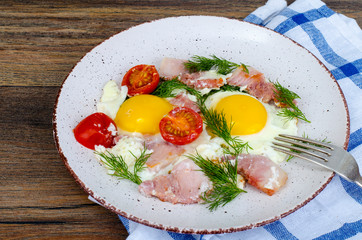 Plate with fried eggs,ham and tomatoes for breakfast