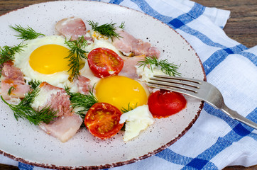 Plate with fried eggs,ham and tomatoes for breakfast