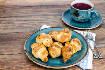 Homemade mini croissants with sugar and cinnamon, wooden background
