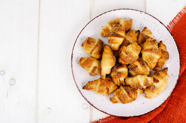 Homemade mini croissants with sugar and cinnamon, wooden background
