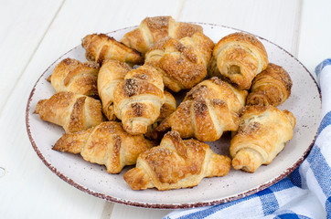 Homemade mini croissants with sugar and cinnamon, wooden background