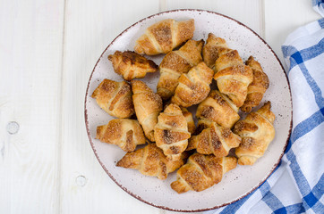 Homemade mini croissants with sugar and cinnamon, wooden background