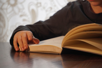 Boy reading book at table.