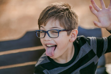 little boy in glasses making silly faces and sticking tongue out