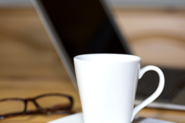 Eine Tasse Kaffee, Lesebrille und ein Computer im Büro