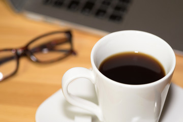 Eine Tasse Kaffee, Lesebrille und ein Computer im Büro