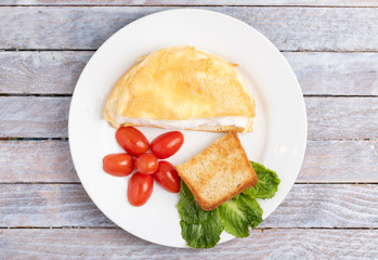 rustic wooden table and omlette on plate, top view