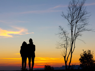 Fototapeta na wymiar Silhouette of two girl standing on the mountain at the sunset or sunrise time.