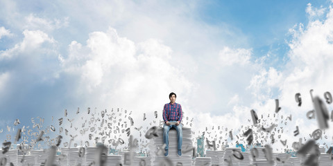 Attractive man sitting on pile of paper documents.