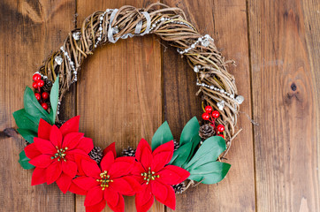 homemade christmas wreath with red flowers on wooden background, place for text