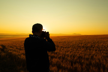 Man take a photo in sunrise in field